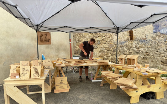 Visuel de Vincent sur son stand en foire entouré d'objets bois
